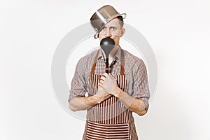 Fun mad man in striped apron with ladle, silver stainless glossy aluminium empty stewpan, pan or pot on head isolated on