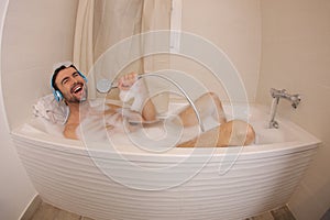 Fun man doing karaoke in the bathtub