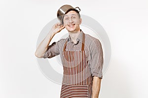 Fun man in striped apron with silver stainless glossy aluminium empty stewpan, pan or pot on head isolated on white