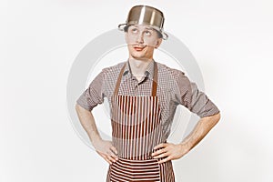 Fun man in striped apron with silver stainless glossy aluminium empty stewpan, pan or pot on head isolated on white
