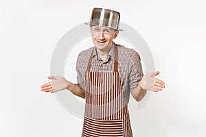 Fun man in striped apron with silver stainless glossy aluminium empty stewpan, pan or pot on head isolated on white