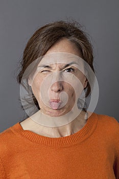 Fun middle aged woman joking, winking and sticking out tongue