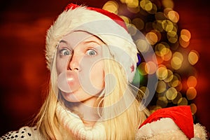 Only fun on my mind. Girl Santa claus making big bubble with gum. Funny face close up. Adorable woman blowing bubble