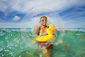 Fun in ocean - boy with sunglasses and yellow inflatable duck