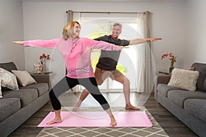 Fun older married couple having fun exercising together indoors, struggling, motivating each other with support for a healthy life