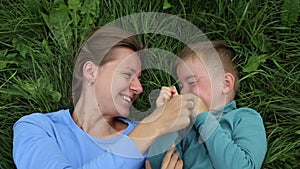 Fun pastime of mother and son. Mom and three-year-old son lie on the grass and have fun