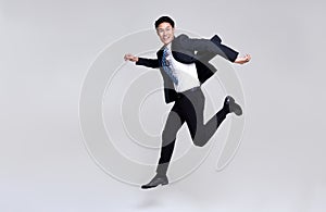 Fun portrait of happy energetic young Asian businessman jumping in mid-air isolated on studio white background