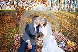 Fun portrait of happy wedding couple in autumn forest, sitting o