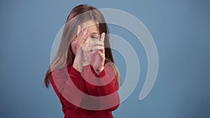 Fun, pretty caucasian girl in red sweater, fooling, looking at camera, inflate cheeks, isolated over pastel blue