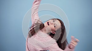 Fun, pretty teen girl in bright sweater, fooling, looking at camera, inflate cheeks, isolated over pastel blue