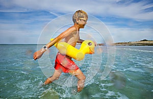 Fun at sea - boy in sunglasses swim with inflatable duck