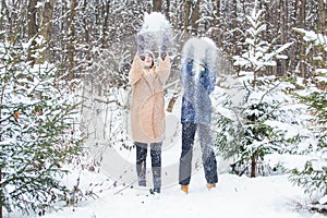 Fun and season concept - Happy mother and son having fun and playing with snow in winter forest