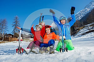 Fun on ski vacation mom and kids sit in snow with skies