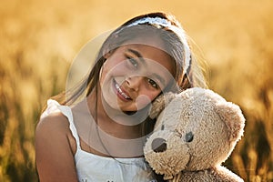 Fun in the sun with Ted. Portrait of a cute little girl playing with her teddybear in a cornfield.