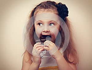 Fun surprising kid girl eating dark chocolate. Vintage closeup