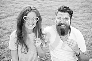 Fun Valentines props. Bearded man and sexy girl smiling with fancy party props on green grass. Funny couple holding