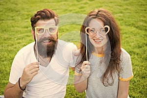 Fun Valentines props. Bearded man and sexy girl smiling with fancy party props on green grass. Funny couple holding