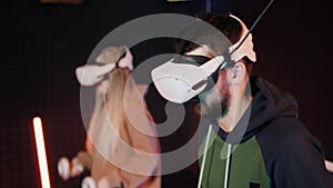 Fun virtual reality competition. Adult couple plays oculus VR drums. Neon light.