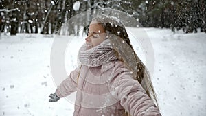 Fun in winter forest - girl spinning under falling hoarfrost