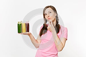 Fun woman holds row of green, red, yellow detox smoothies in bottles isolated on white background. Proper nutrition