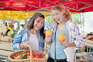 fun women choosing fruit outdoors in bio market