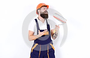 Fun at work. Builder holding paint roller as microphone. Young man singing lyric song over white background