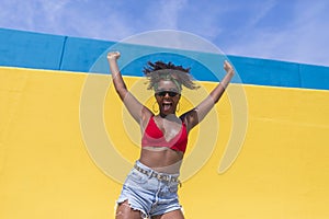 Fun young afro american woman laughing with arms raised