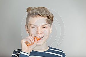 Fun young boy biting into a fresh raw carrot