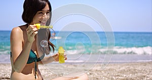 Fun young woman blowing bubbles on a beach
