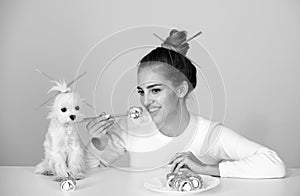 Fun young woman with pet puppy eating sushi on gray background. Closeup portrait of beauty woman and dog eating sushi