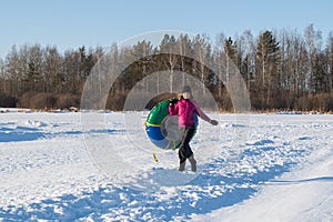 Fun Young woman snow tube in winter park. Leisure on nature, snow slide skiing. Concept of interactive entertainment.