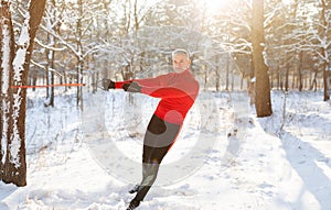 Functional fitness workout. Full length of mature man using bodyweight resistance straps at winter forest, copy space