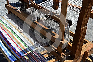 Functional historical wooden hand-loom weaving colorful mat with vertical lines displayed on festival of medieval and traditional