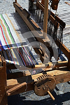 Functional historical wooden hand-loom weaving colorful mat with vertical lines displayed on festival of medieval and traditional