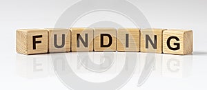 FUNDING word written on wooden cube blocks on white glossy background