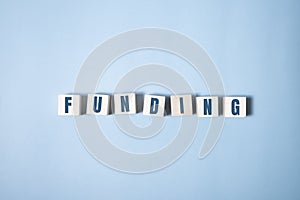 FUNDING word written on wooden cubes on blue