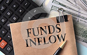 FUNDS INFLOW - words on brown paper on the background of calculator and banknotes photo