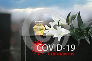 Funeral ceremony devoted to coronavirus victims. White lilies and candle on tombstone