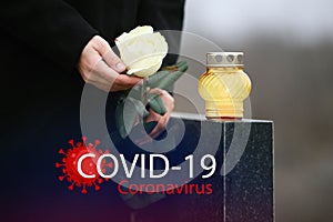 Funeral ceremony devoted to coronavirus victims. Woman holding rose near tombstone with candle, closeup