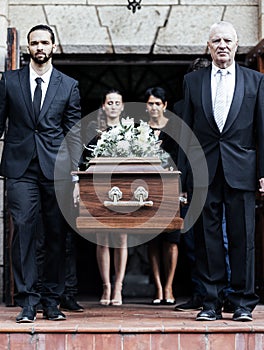 Funeral, church and people with a coffin, family and mourning in emotional distress. Church service, casket and burial