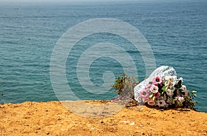 Funeral flowers at the beach. Flower bouquet on doom place, memory, Atlantic ocean, spanish seashoore. copy space,  Funeral symbol