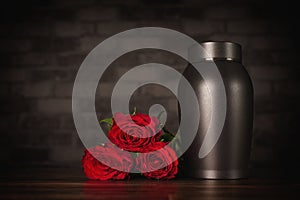 Funeral mourning urn next to a bunch of roses.