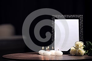 Funeral photo frame with black ribbon, roses and candles