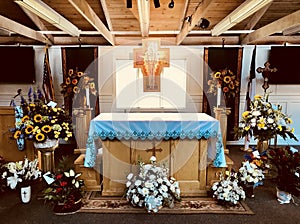 A funeral service is prepared in a church with a cross, flowers, and a flag