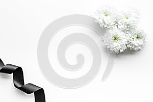 Funeral symbols. White flower near black ribbon on white background top view copy space