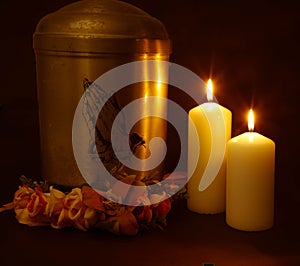 Funeral urn with praying hands and burning candles.