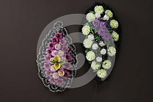 Funeral wreaths of plastic flowers hanging on dark grey wall