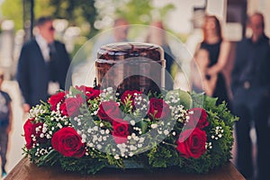 Funerary urn with ashes of dead and flowers at funeral