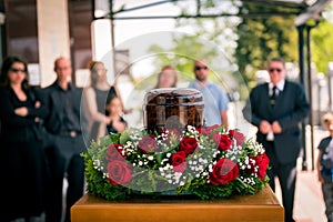 Funerary urn with ashes of dead and flowers at funeral