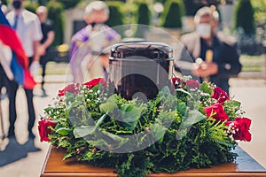 Funerary urn with ashes of dead and flowers at funeral